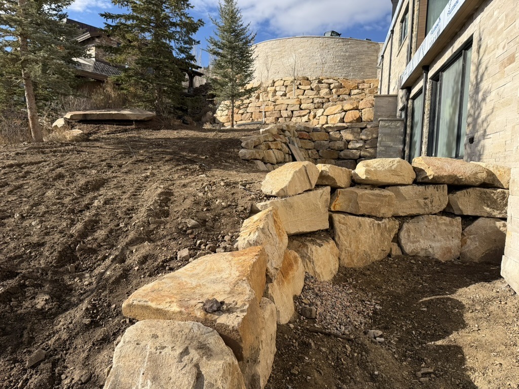 Stone retaining wall near house in rural setting.
