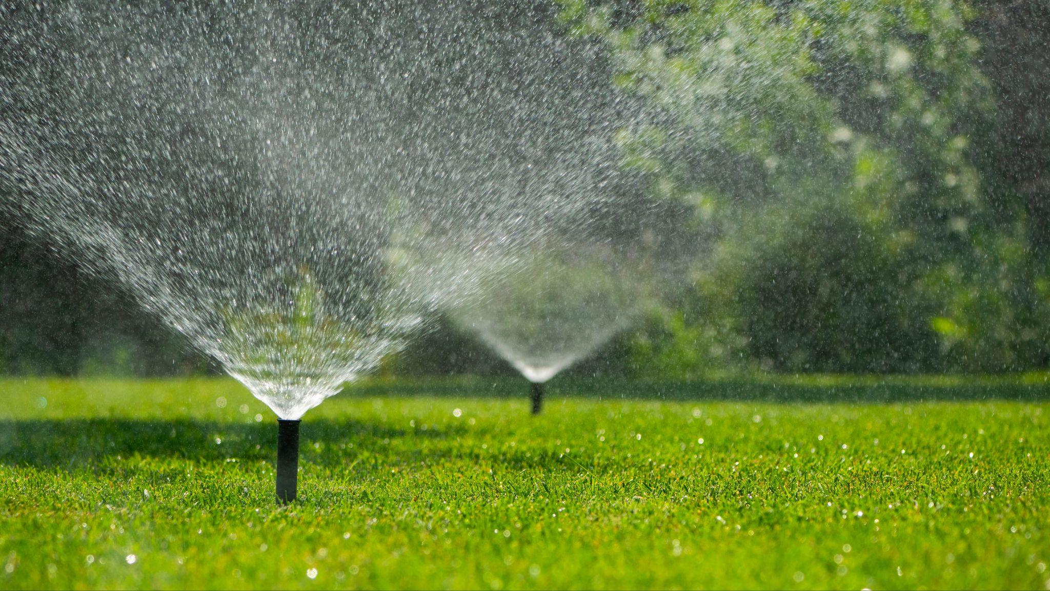 Commercial irrigation sprinklers watering a green lawn, demonstrating efficient landscape irrigation and water management.