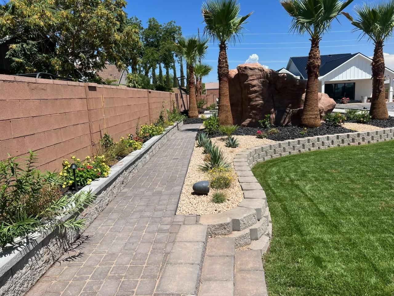 Commercial property walkway with palms, stone beds, and desert plants