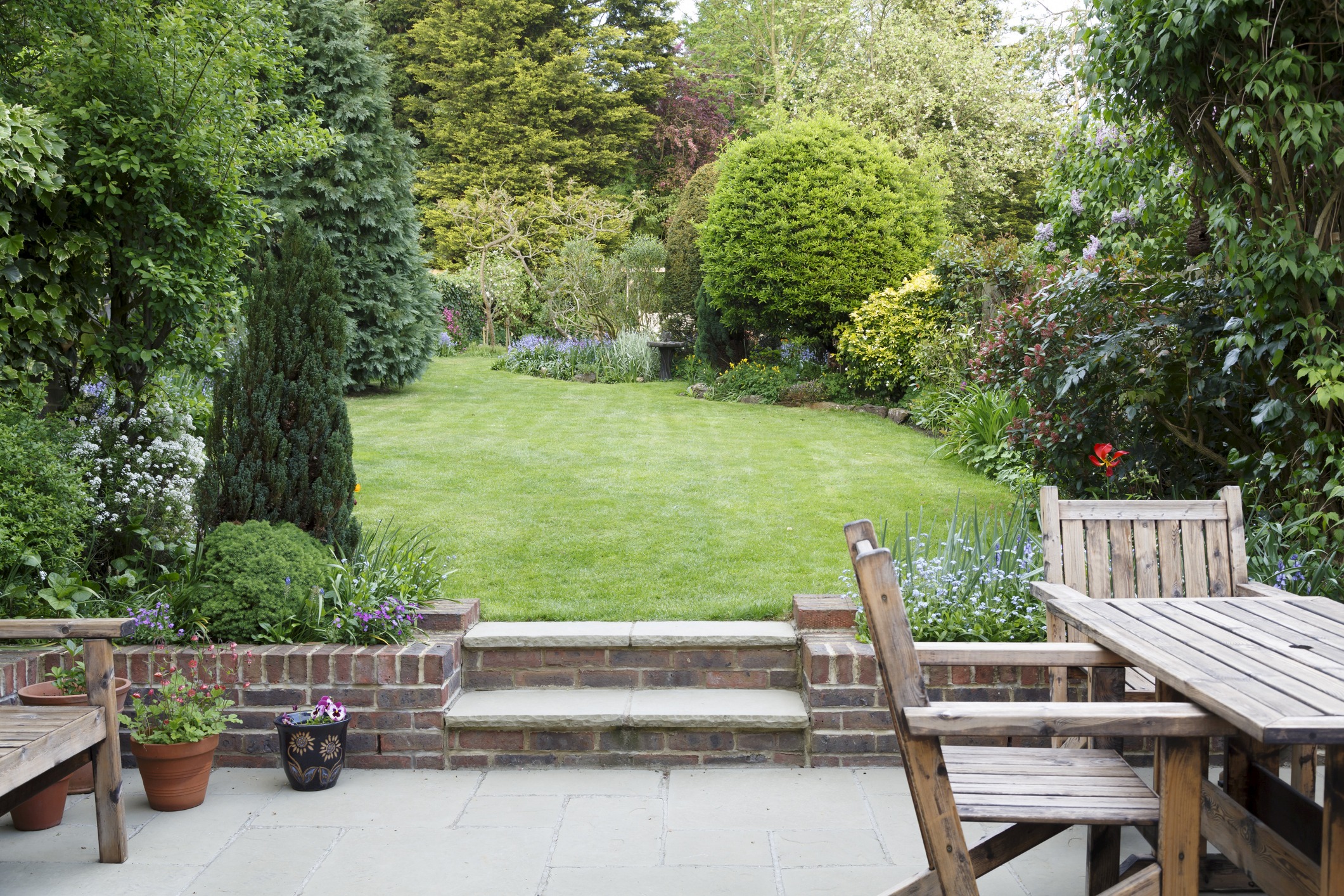 Backyard garden with patio furniture and lush greenery.
