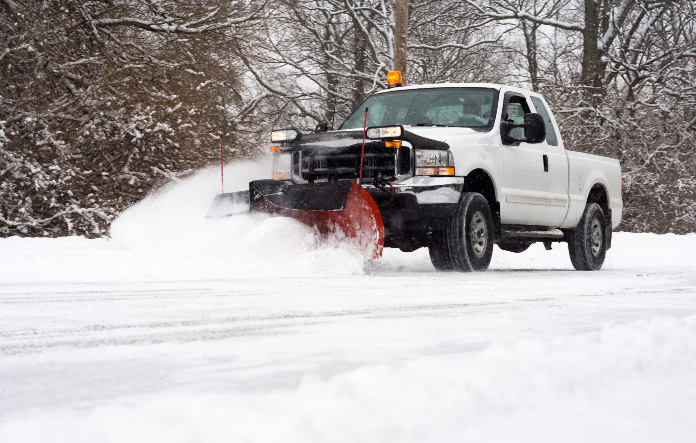 Truck with plow clearing snowy road.