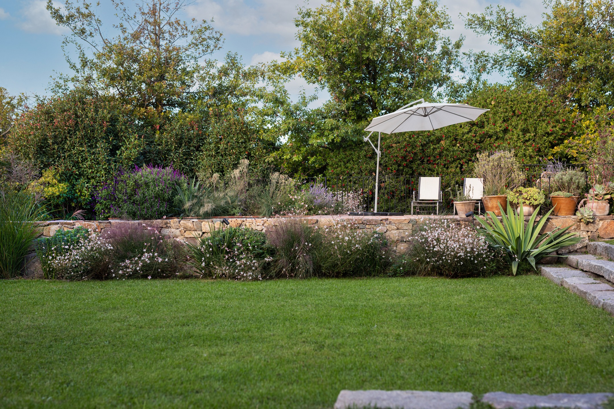Lush garden with patio and umbrella shade.