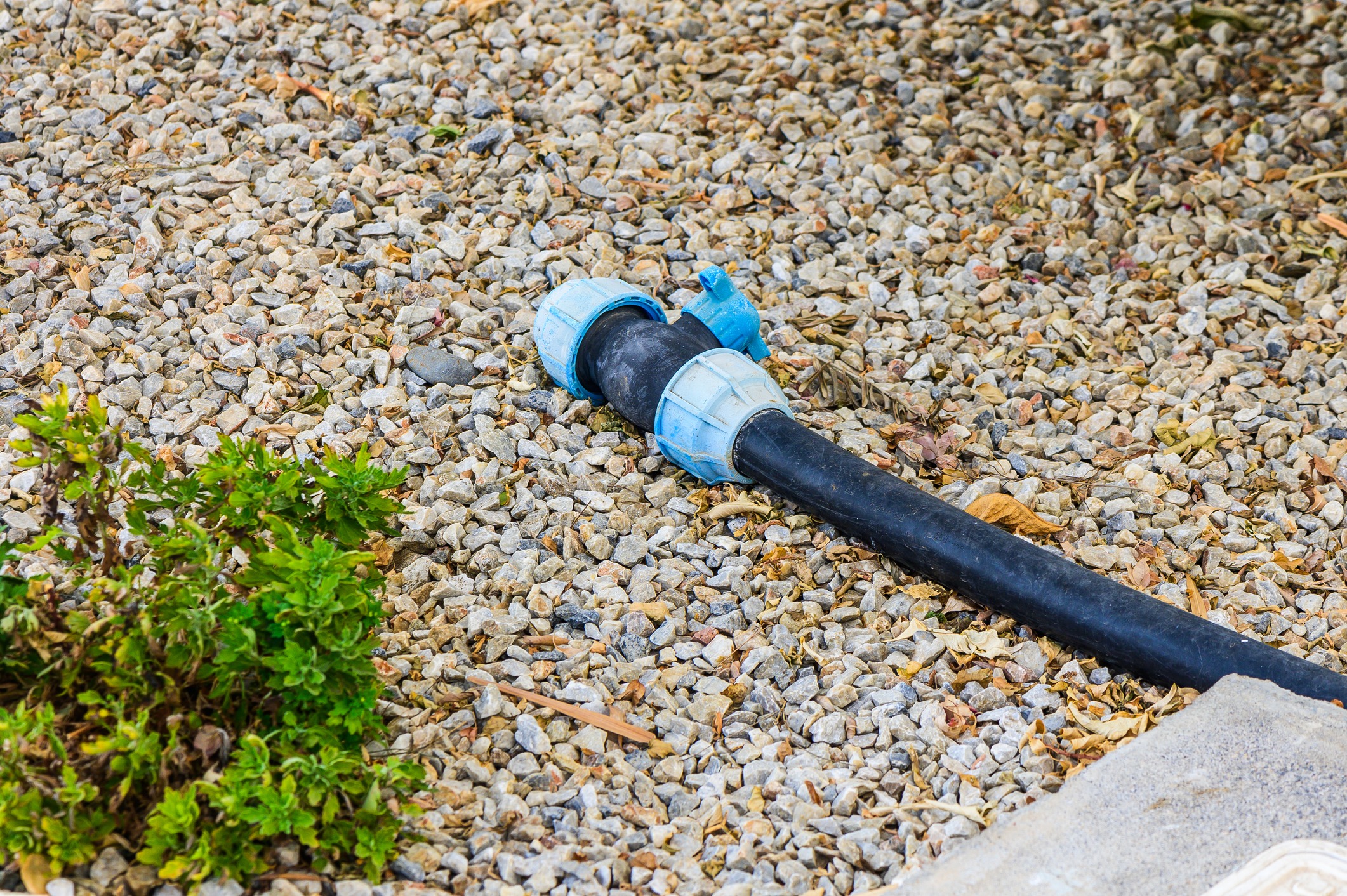 Outdoor water hose on gravel ground.
