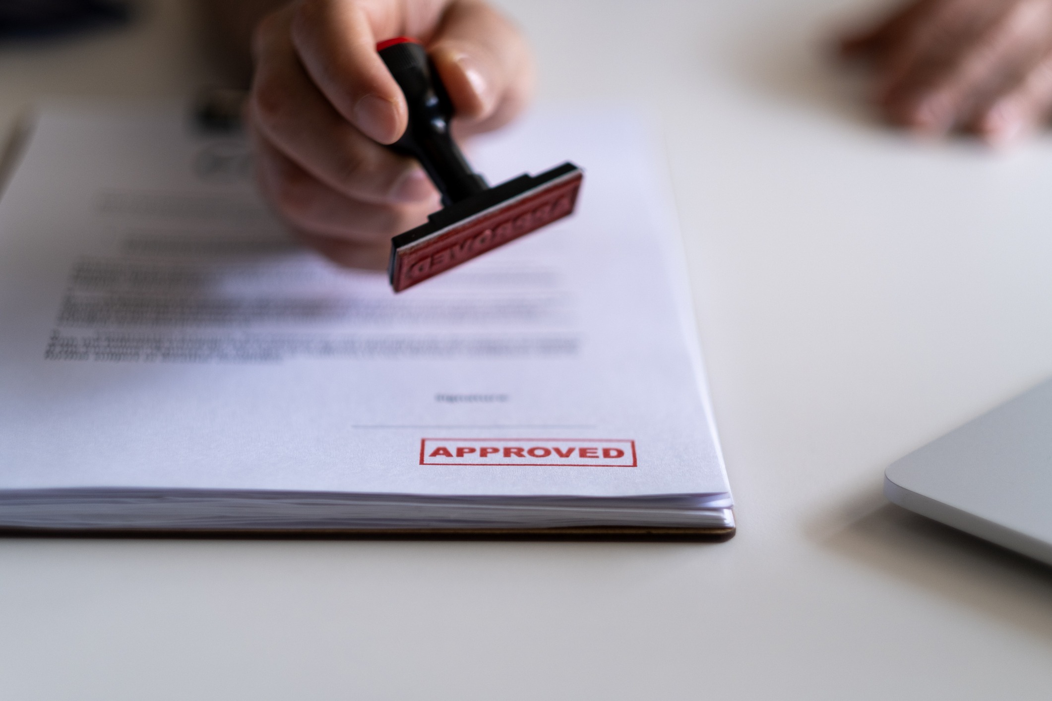 Hand stamping 'approved' on a document.